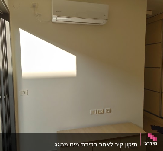 קיר לבן עם מזגן תלוי וצל על הקיר